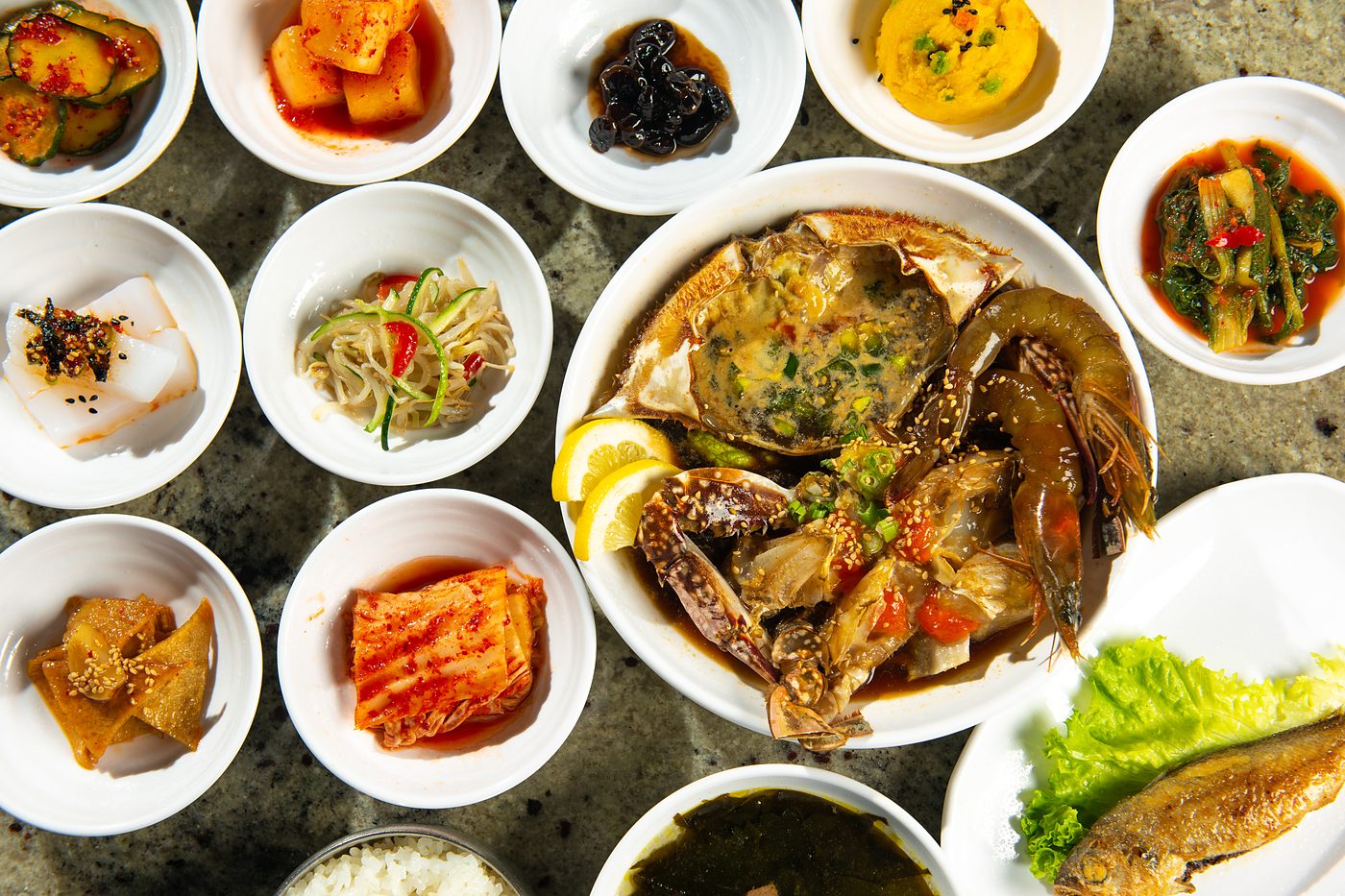 Banchan side dishes surrounding soy marinated raw crab