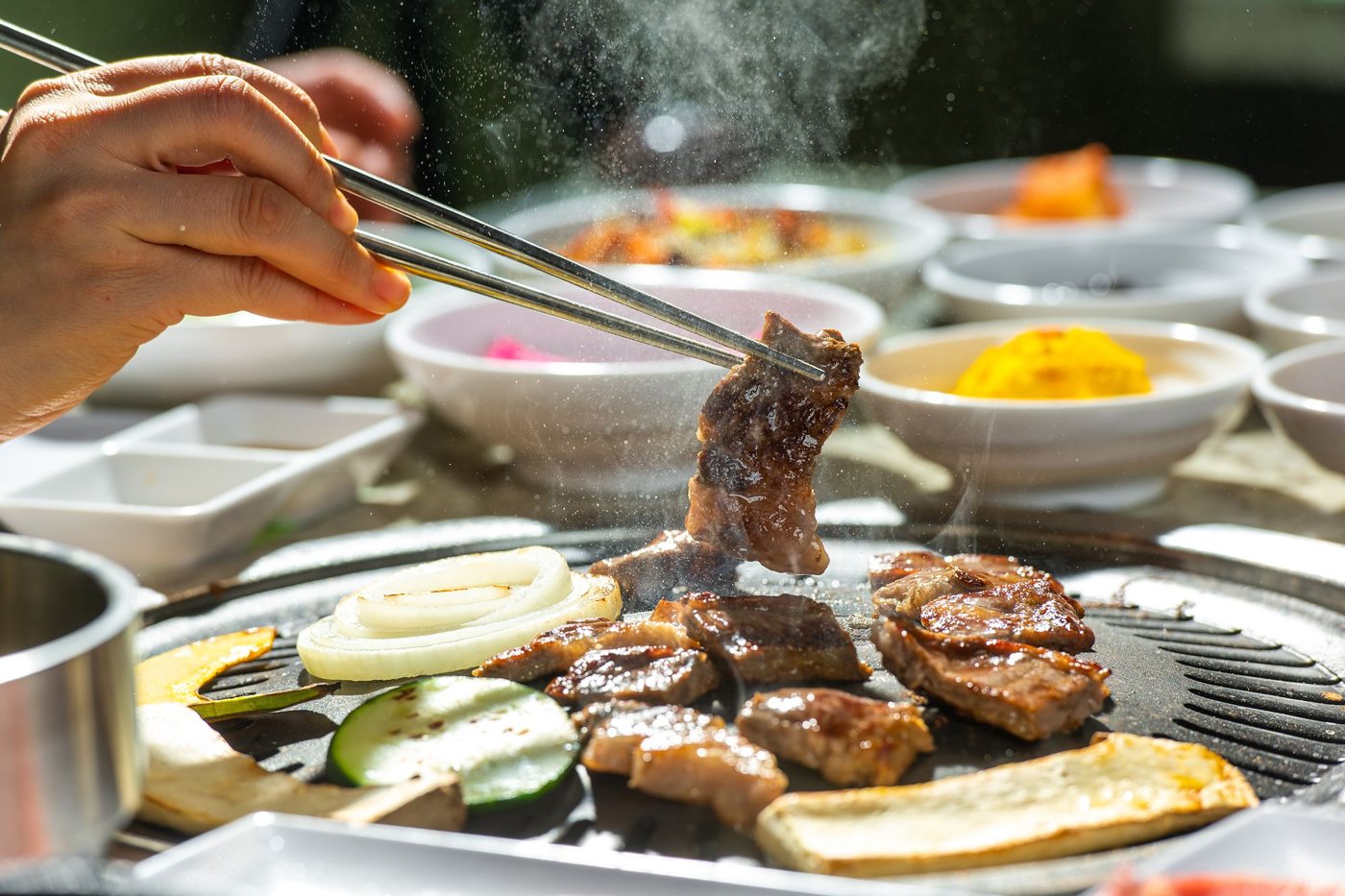 Tongs turning short rib on the tabletop grill